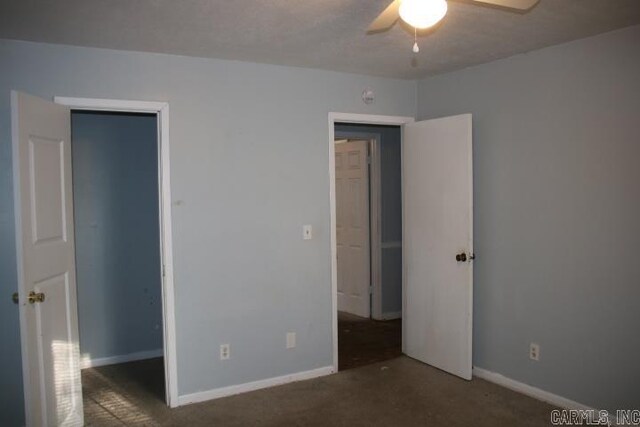 unfurnished bedroom with dark carpet and ceiling fan