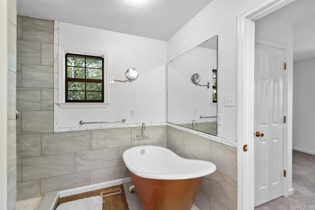 bathroom featuring tile walls, a textured ceiling, and a tub