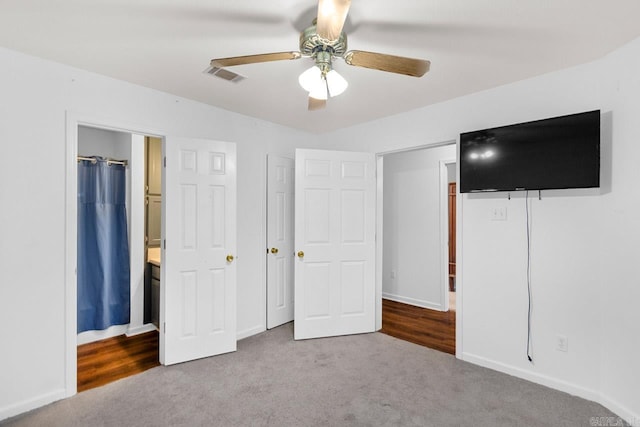 unfurnished bedroom featuring ceiling fan, light colored carpet, and ensuite bathroom