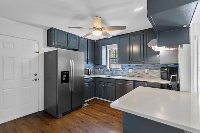 kitchen with ceiling fan, sink, dark wood-type flooring, stainless steel appliances, and decorative backsplash