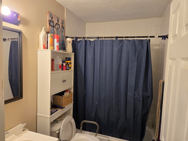 bathroom with shower / bathtub combination with curtain, a textured ceiling, and toilet