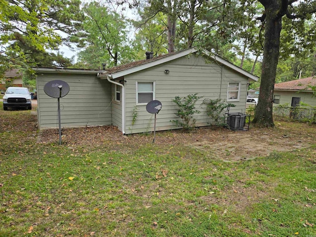 view of side of property with a yard and central AC