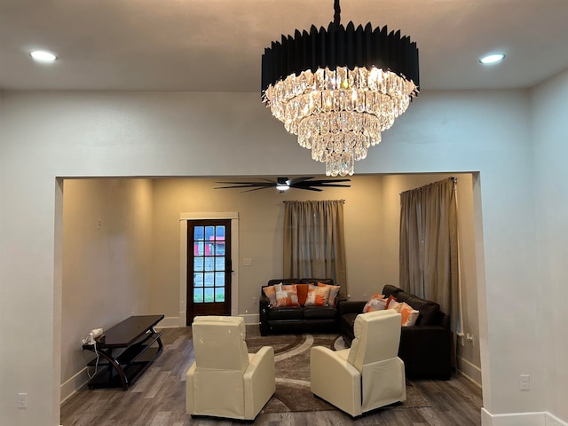 living room with ceiling fan with notable chandelier and hardwood / wood-style floors