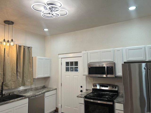 kitchen featuring appliances with stainless steel finishes, hanging light fixtures, sink, and white cabinets