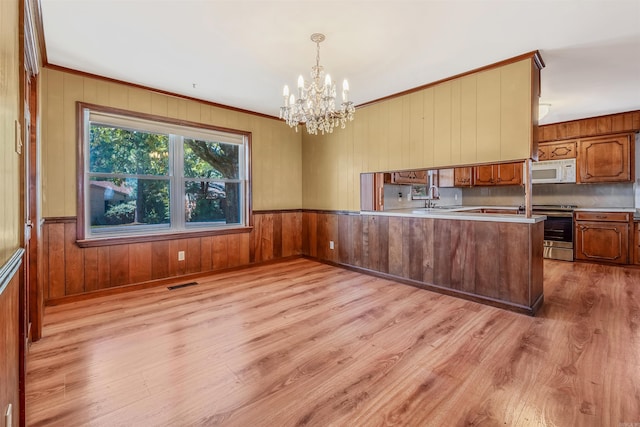 kitchen with light hardwood / wood-style floors, kitchen peninsula, stainless steel range oven, and decorative light fixtures