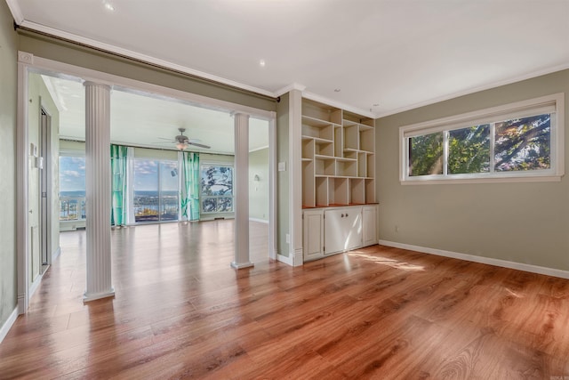 unfurnished living room with light wood-type flooring, ornate columns, ornamental molding, ceiling fan, and built in features