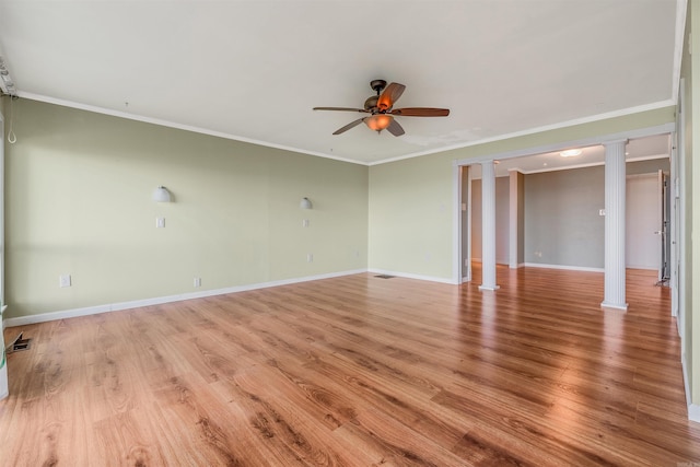 spare room featuring light wood-type flooring, decorative columns, ceiling fan, and crown molding