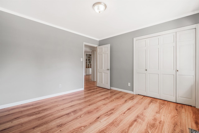 unfurnished bedroom with a closet, light wood-type flooring, and ornamental molding