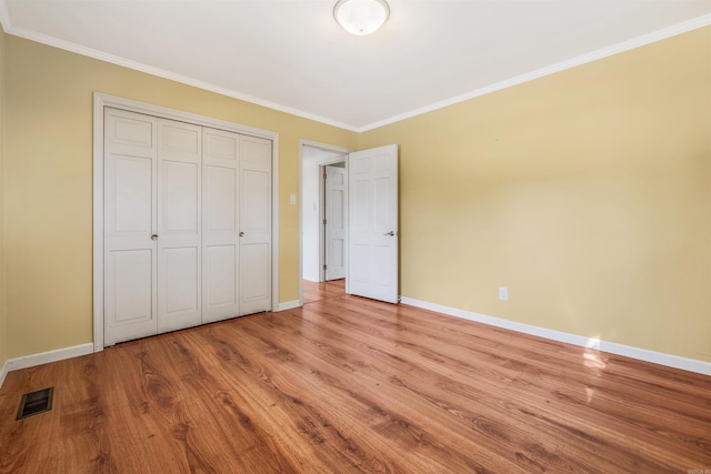 unfurnished bedroom with light wood-type flooring, a closet, and crown molding