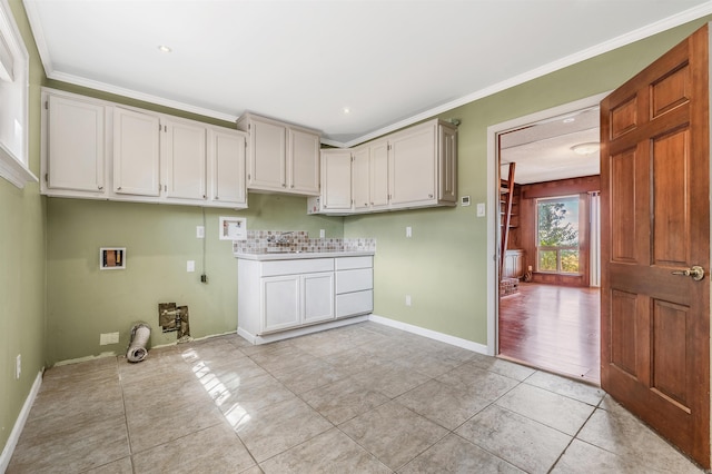 washroom with hookup for a washing machine, light tile patterned floors, crown molding, cabinets, and sink