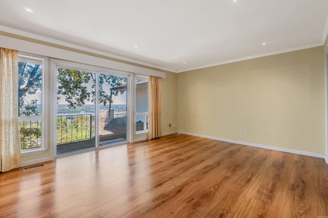 unfurnished room featuring light hardwood / wood-style flooring, ornamental molding, and a healthy amount of sunlight