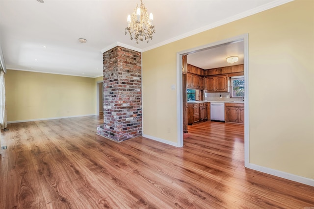 unfurnished living room featuring ornate columns, an inviting chandelier, crown molding, and light hardwood / wood-style floors