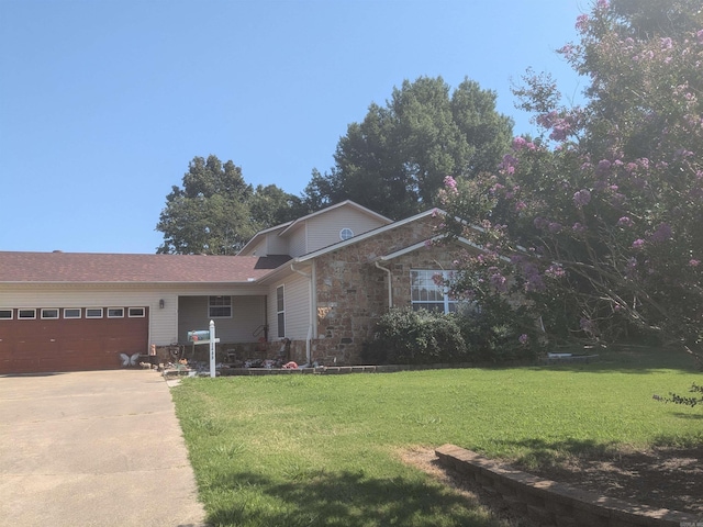 view of front of home featuring a garage, stone siding, driveway, and a front yard