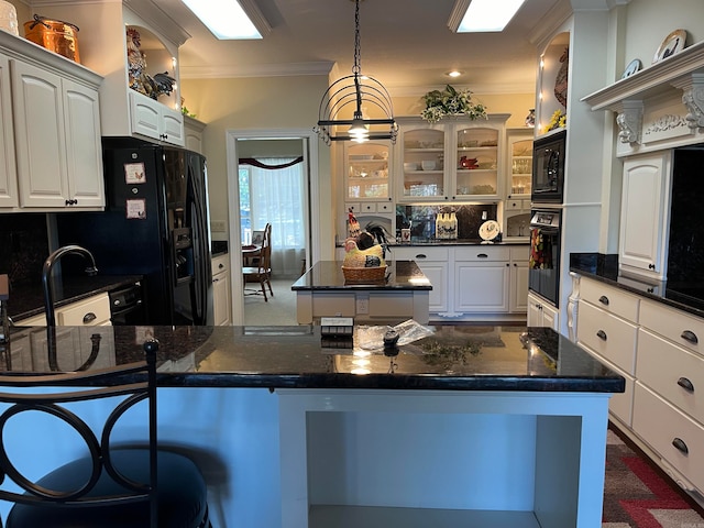 kitchen featuring crown molding, black appliances, a kitchen island, and white cabinetry