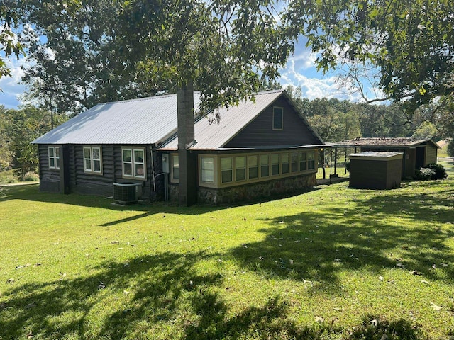 rear view of property with central AC unit and a yard