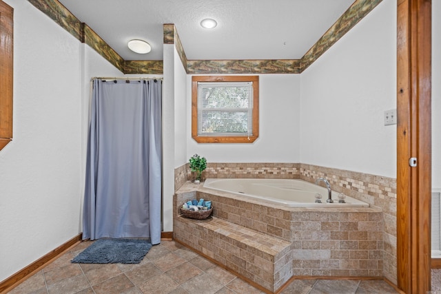 bathroom featuring a textured ceiling and a relaxing tiled tub