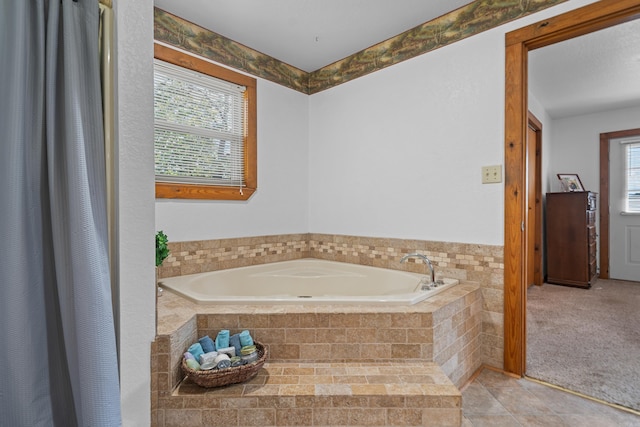 bathroom with a relaxing tiled tub, tile patterned floors, and a healthy amount of sunlight