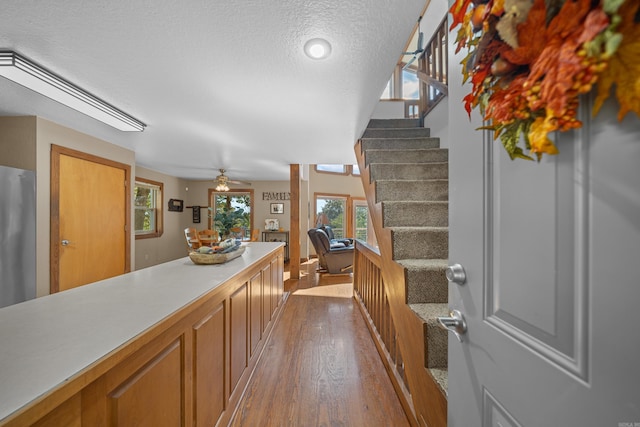 interior space featuring a textured ceiling, stainless steel fridge, hardwood / wood-style floors, and ceiling fan