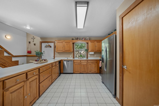 kitchen with stainless steel appliances, kitchen peninsula, light tile patterned flooring, and sink