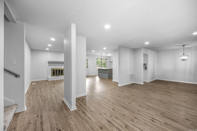 unfurnished living room featuring light wood-type flooring, a fireplace, and a chandelier