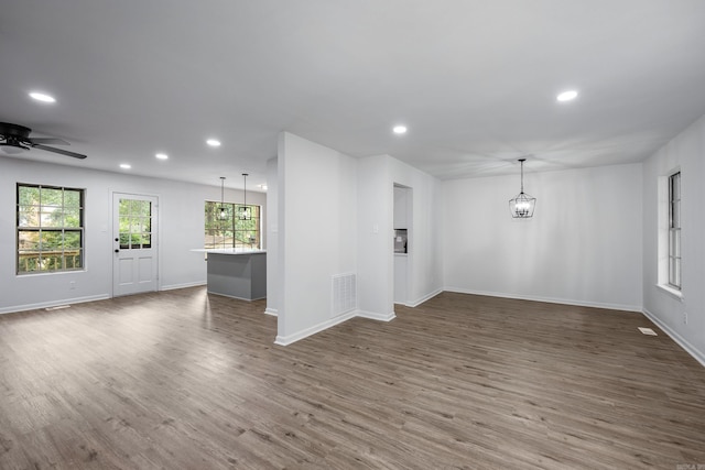 interior space with ceiling fan with notable chandelier and dark wood-type flooring