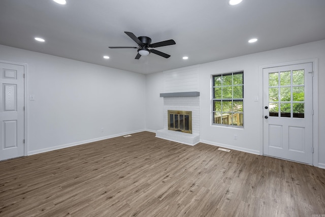 unfurnished living room with hardwood / wood-style floors, ceiling fan, and a brick fireplace