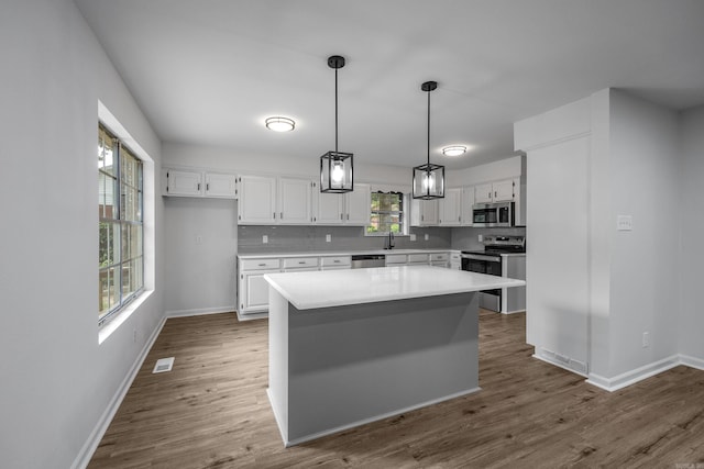 kitchen featuring wood-type flooring, a center island, sink, white cabinets, and stainless steel appliances