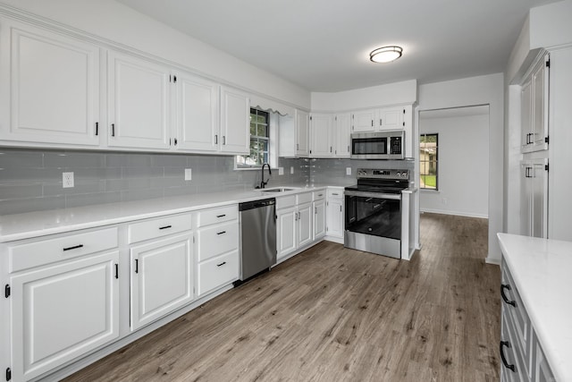 kitchen with white cabinets, light hardwood / wood-style floors, appliances with stainless steel finishes, and sink