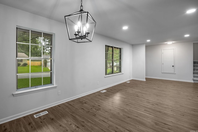 unfurnished dining area featuring dark hardwood / wood-style floors and a chandelier