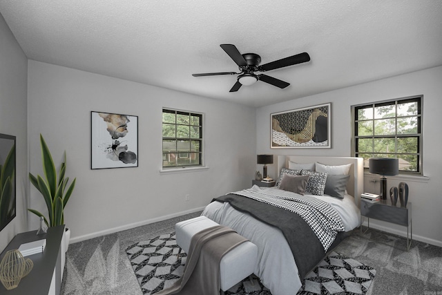 carpeted bedroom with ceiling fan, multiple windows, and a textured ceiling