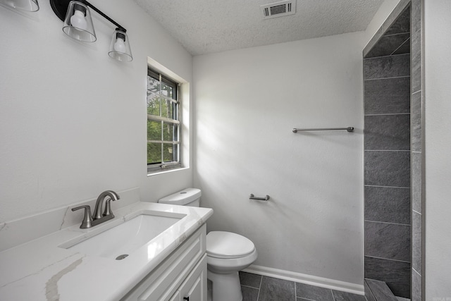 bathroom featuring vanity, toilet, a textured ceiling, and tile patterned floors