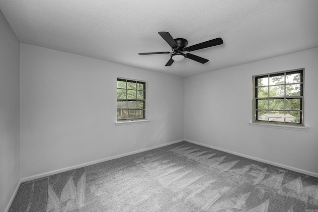 carpeted spare room featuring ceiling fan, a textured ceiling, and a healthy amount of sunlight