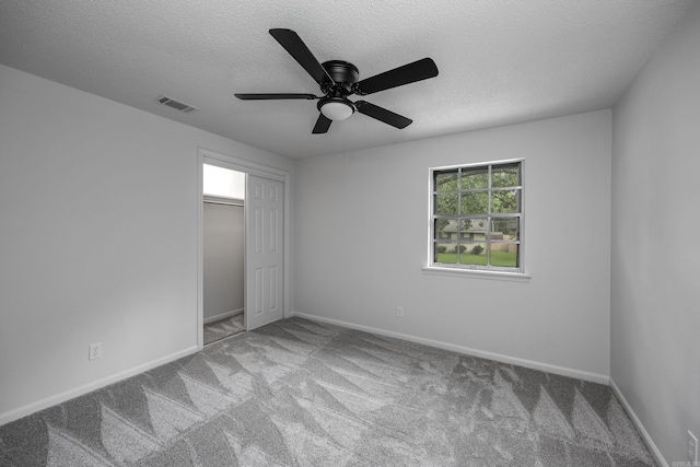 unfurnished bedroom featuring a closet, ceiling fan, carpet floors, and a textured ceiling