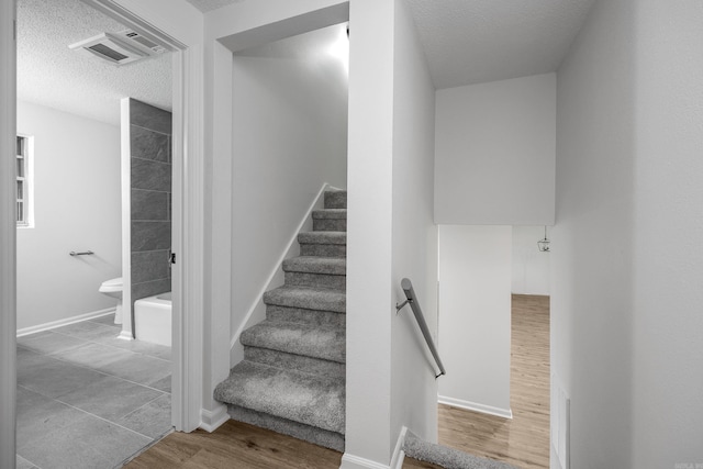 stairs with a textured ceiling and hardwood / wood-style flooring