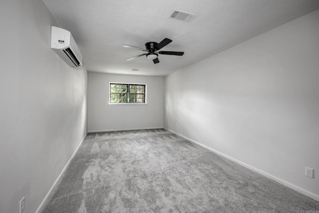 carpeted spare room featuring a textured ceiling, ceiling fan, and a wall mounted air conditioner