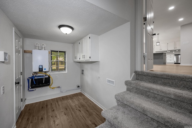 washroom with washer hookup, hookup for an electric dryer, a textured ceiling, gas dryer hookup, and hardwood / wood-style flooring