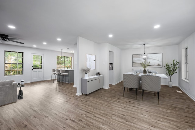 dining area with ceiling fan with notable chandelier and hardwood / wood-style floors