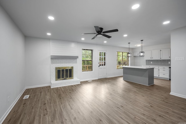 unfurnished living room with a brick fireplace, dark hardwood / wood-style flooring, and ceiling fan