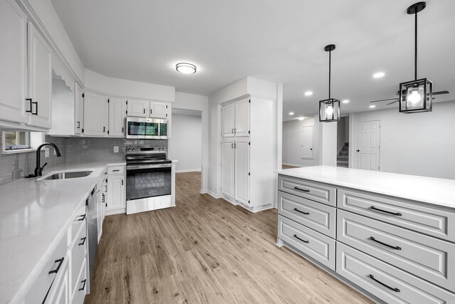 kitchen featuring sink, stainless steel appliances, light hardwood / wood-style floors, and white cabinetry