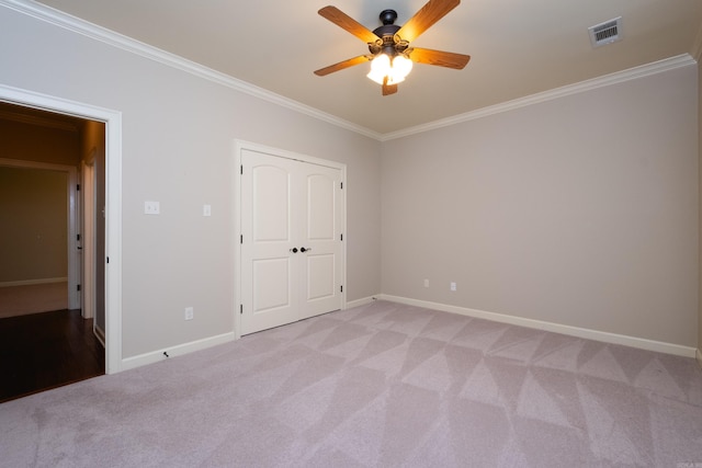 unfurnished bedroom with ceiling fan, light colored carpet, and ornamental molding