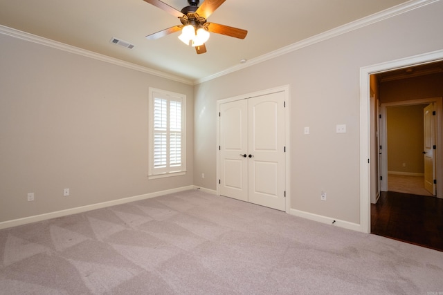 unfurnished bedroom with ceiling fan, light colored carpet, a closet, and crown molding