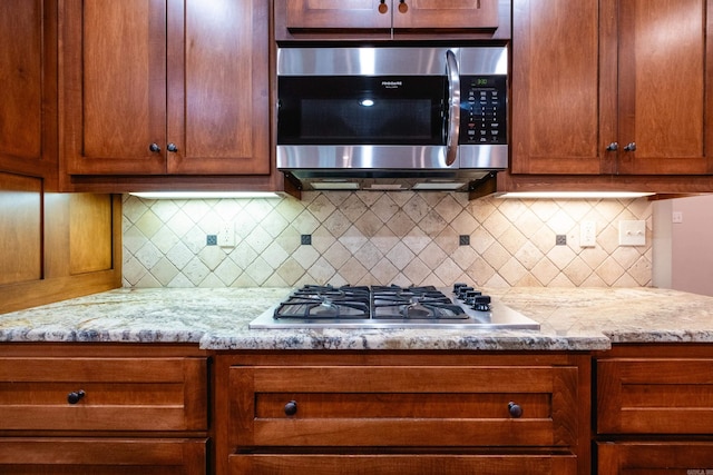 kitchen with backsplash, light stone countertops, and stainless steel appliances