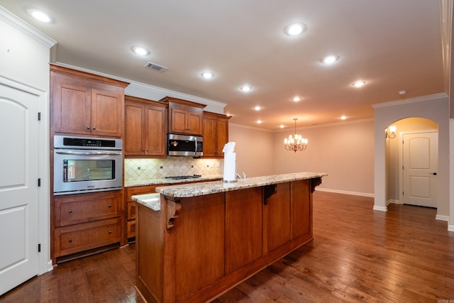 kitchen featuring a breakfast bar, light stone counters, dark wood-type flooring, an island with sink, and stainless steel appliances