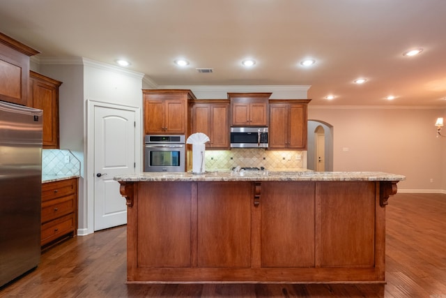 kitchen featuring light stone counters, an island with sink, appliances with stainless steel finishes, a kitchen bar, and dark hardwood / wood-style flooring