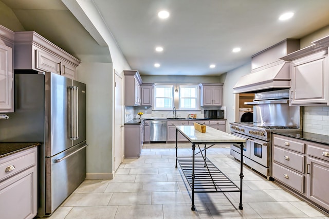 kitchen featuring custom exhaust hood, sink, appliances with stainless steel finishes, dark stone countertops, and decorative backsplash