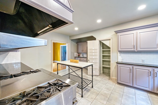 kitchen with backsplash, stainless steel range, light tile patterned flooring, and extractor fan