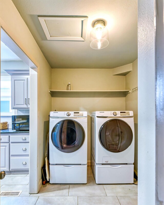 clothes washing area featuring light tile patterned floors and washing machine and clothes dryer