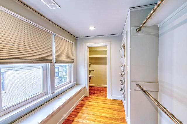 hallway featuring crown molding and light hardwood / wood-style flooring