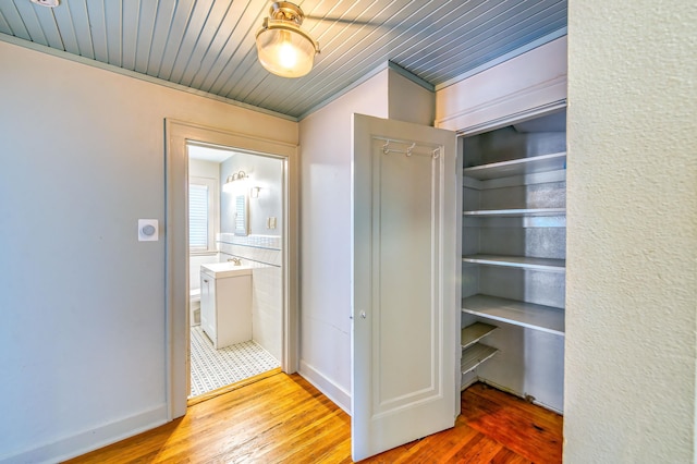 hall featuring sink, crown molding, hardwood / wood-style floors, and wooden ceiling