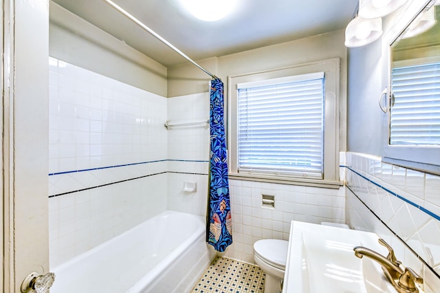 full bathroom with tile walls, toilet, and shower / bathtub combination with curtain